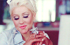 Christina Aguilera on a white desktop computer having a smug look on her face after clicking the left mouse button.