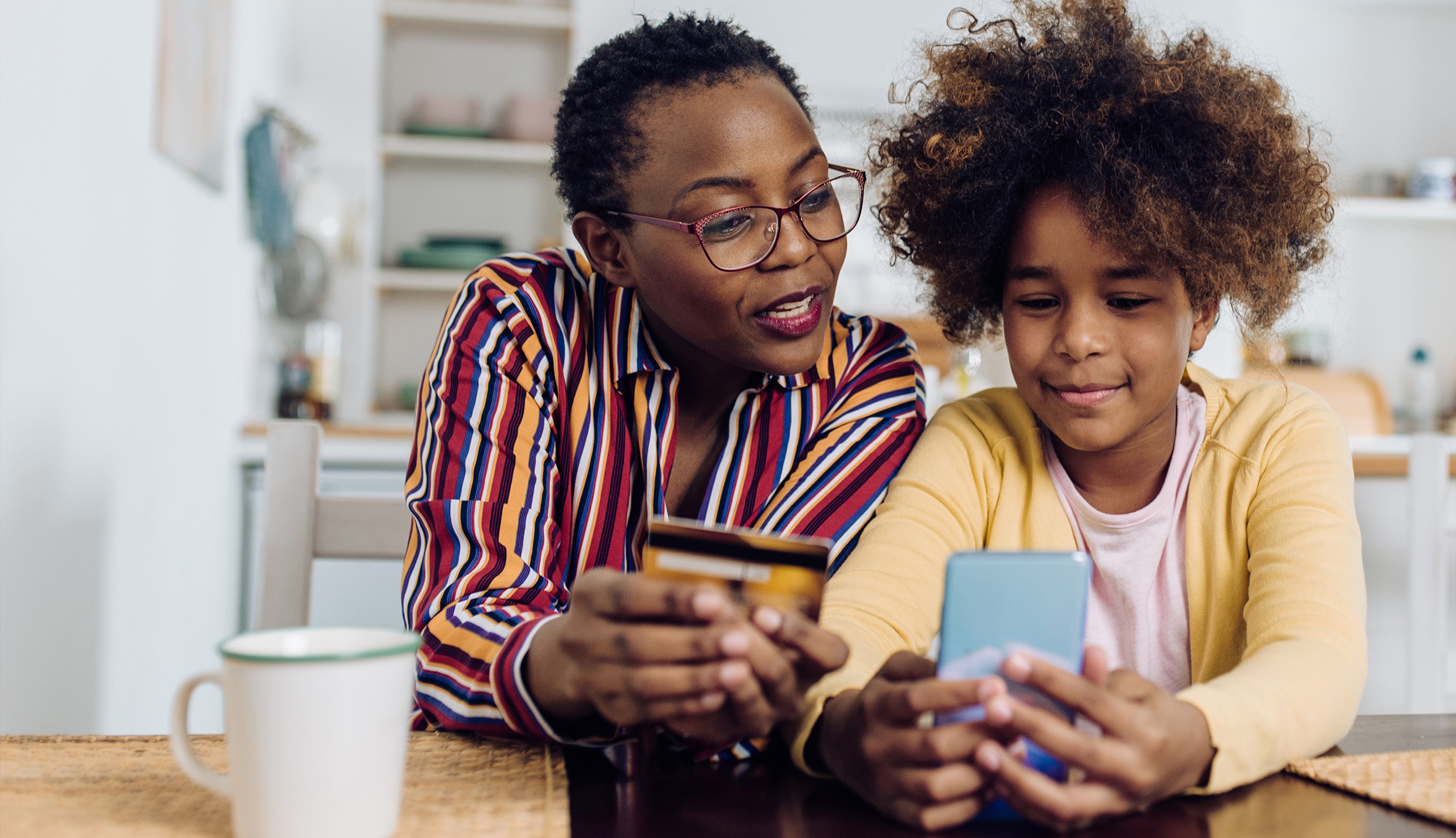 A parent's child helping them use a mobile banking app on a phone